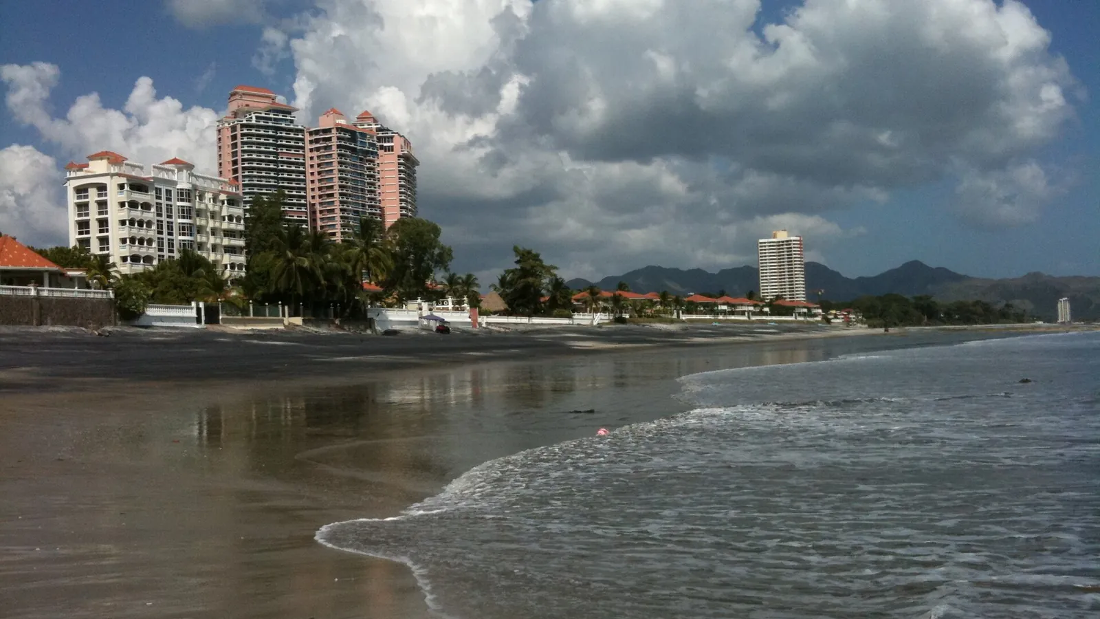 Waves washing onto the wide beach at Coronado, Panama, with beachfront towers behind